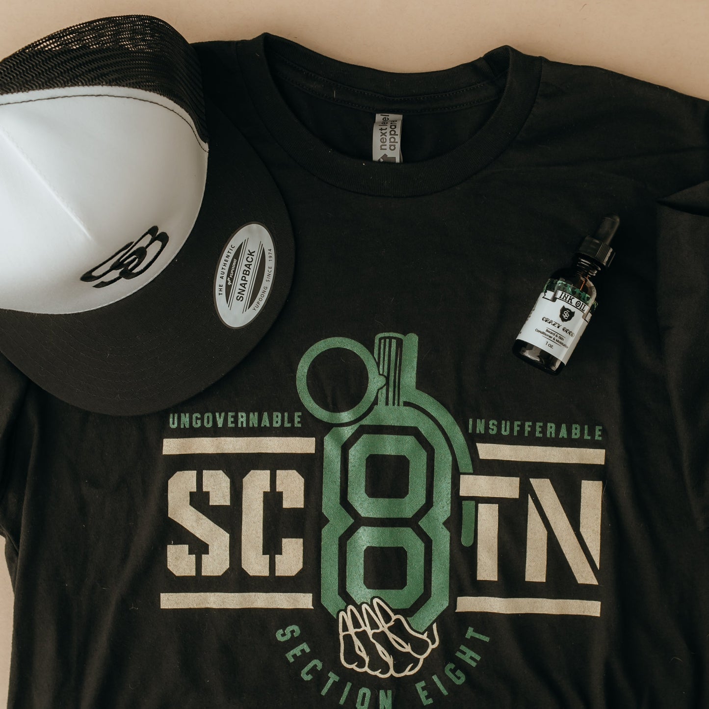 Black t-shirt with graphic design and cap on a beige background